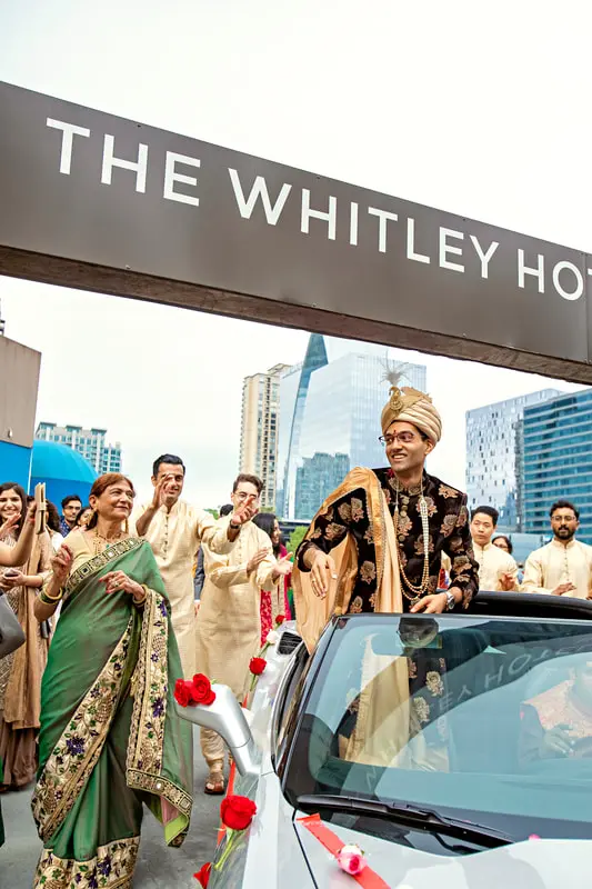 Indian groom in sherwani leads a lively baraat outside The Whitley Hotel in Atlanta, surrounded by joyful guests