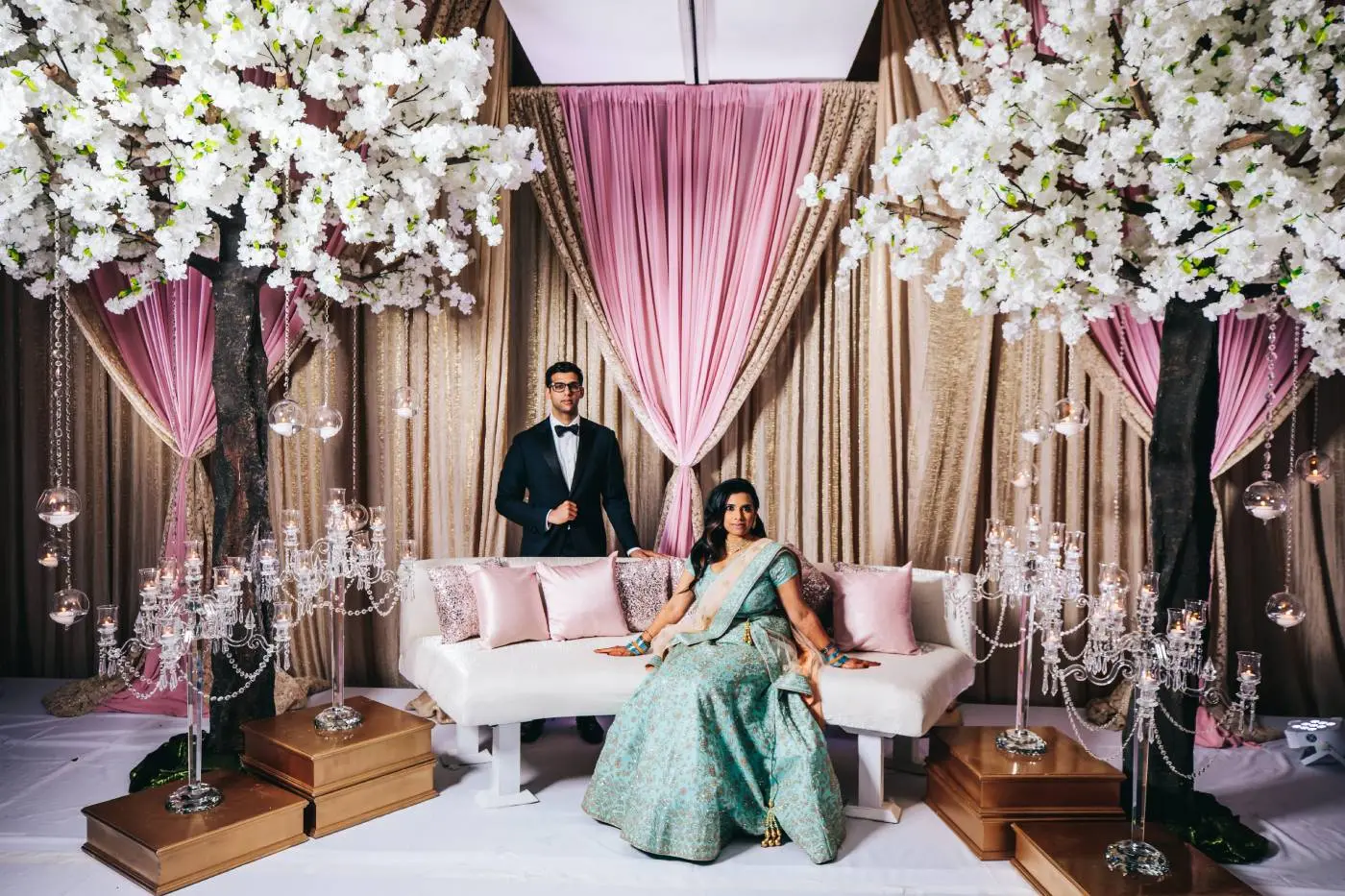 Bride and groom pose under floral canopy at luxurious Indian wedding in Georgia