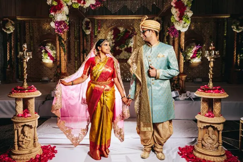 South Asian couple holding hands beneath a vibrant mandap during traditional Hindu wedding ceremony in Georgia