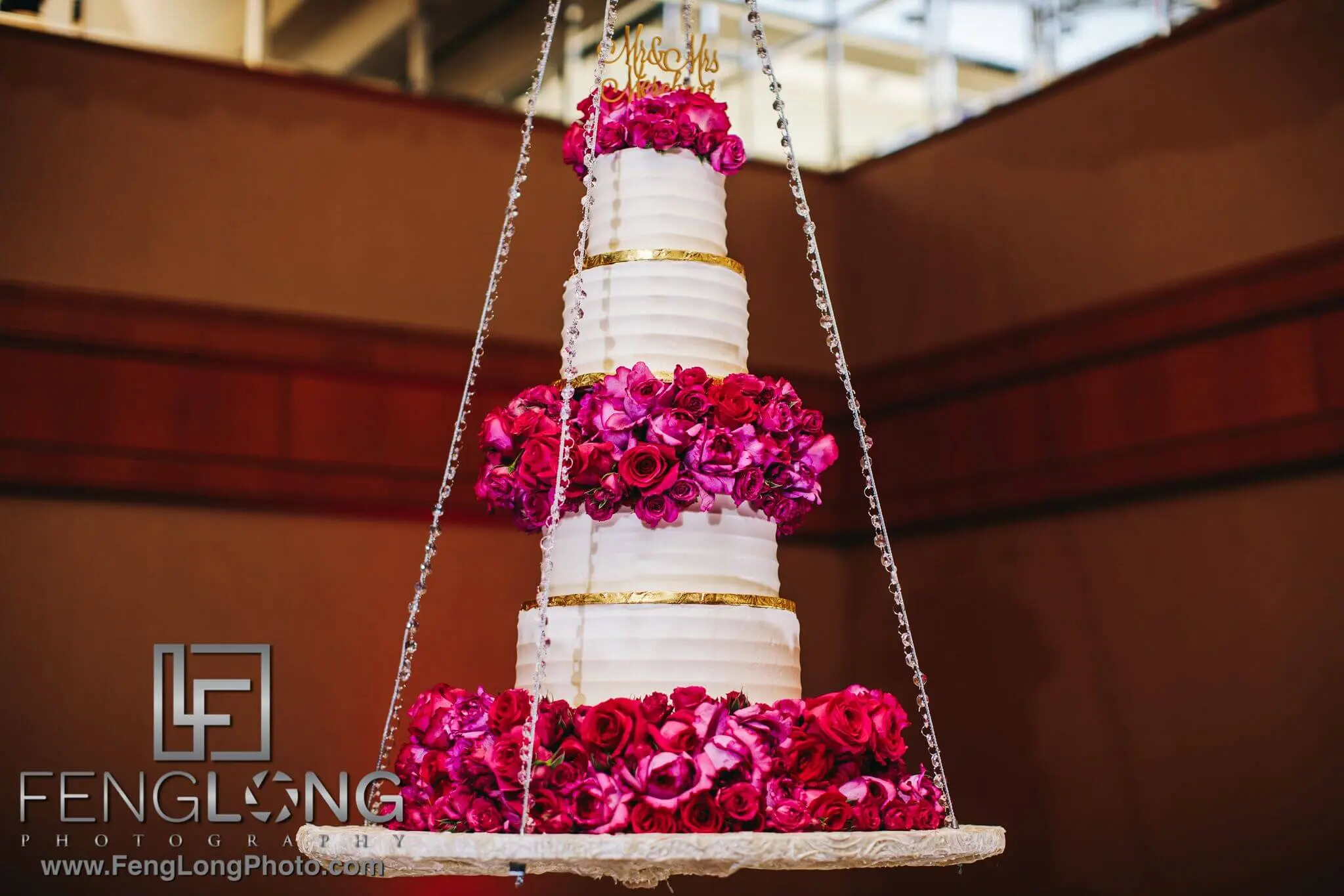 Suspended wedding cake at fusion reception in Atlanta, with pink flowers and a gold Mr & Mrs topper