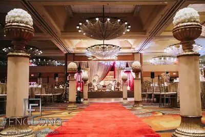 High-end wedding venue with red carpet aisle and floral altar under chandeliers at Atlanta South Asian wedding
